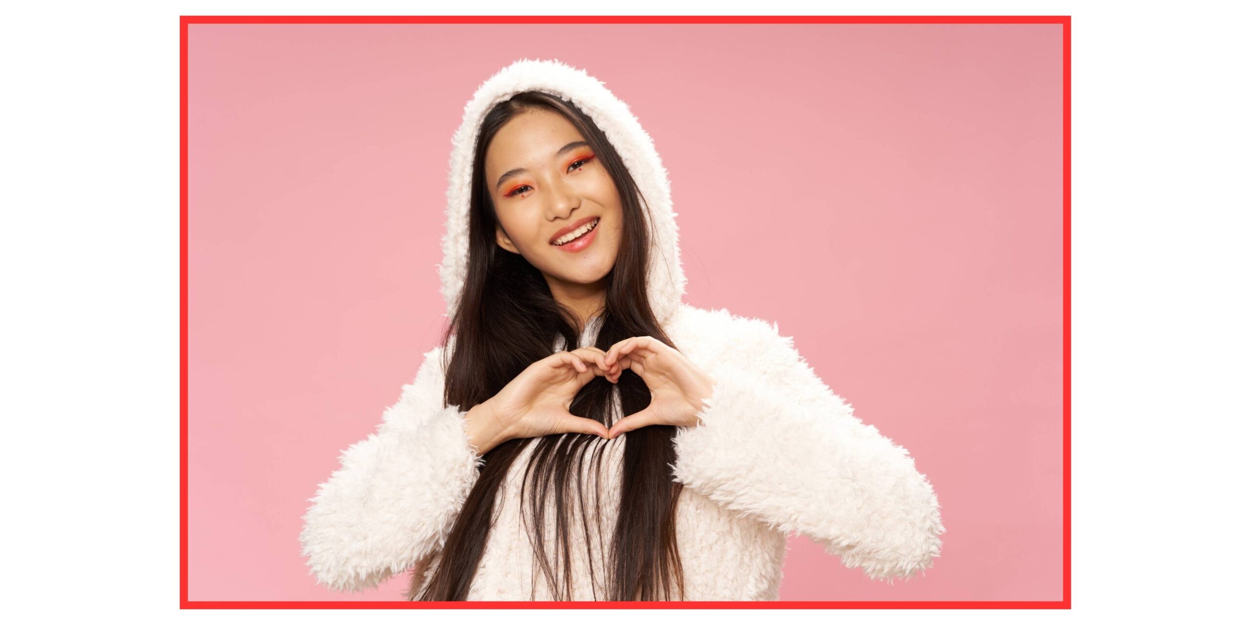 Chica joven China con abrigo de borreguito hace un corazón con las manos